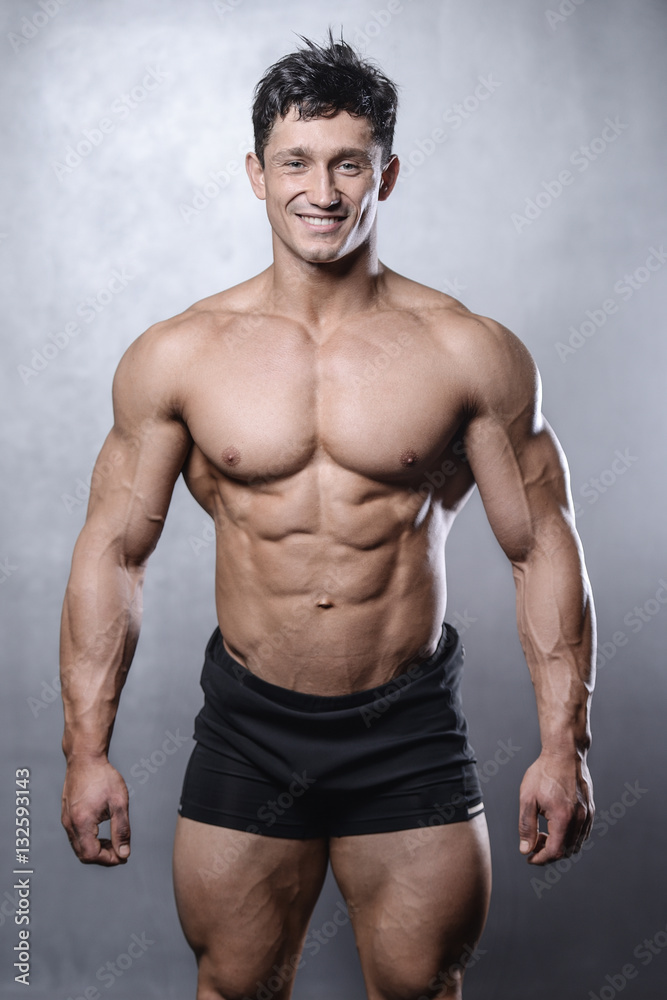 beautiful fitness male model posing in studio on white grey back