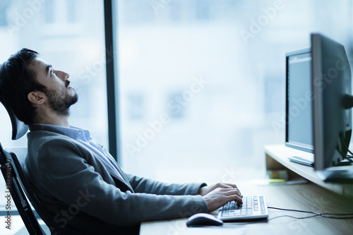 Overworked tired employee at workplace in office being unhappy photo