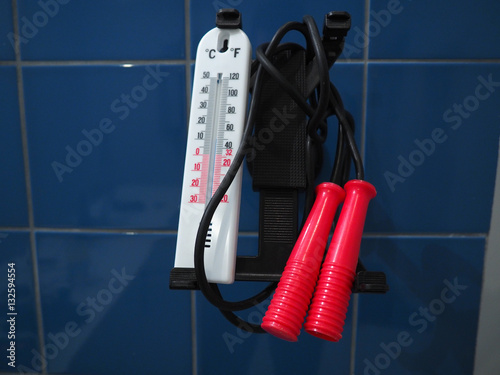 Jump rope and thermometer hanging against blue wall