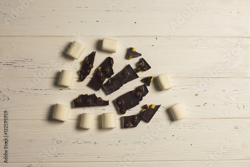 Peices of chocolate with nuts and white marshmallow on wooden background photo