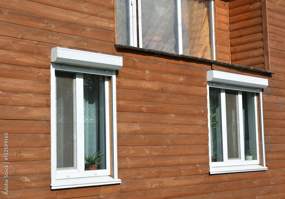 Fototapeta premium Windows with rolling shutter protection on the wooden house facade exterior