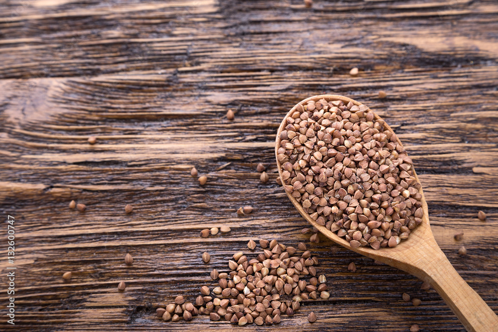 raw buckwheat in a wooden spoon raw buckwheat in a wooden spoon