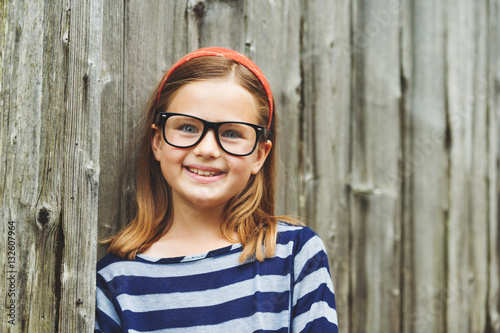 Outdoor portrait of a cute little 9 year old girl wearing eyeglasses