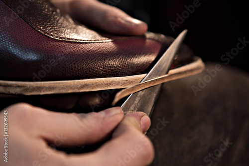 shoemaker makes shoes for men He cuts off excess and forms  shoe soles © Kateryna
