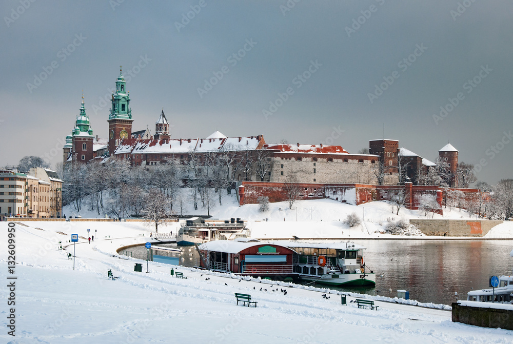 Historic royal Wawel Castle and Cathedral in Cracow, Poland, with Vistula River and harbor on a cloudy day in winter in last sunlight before the snowfall