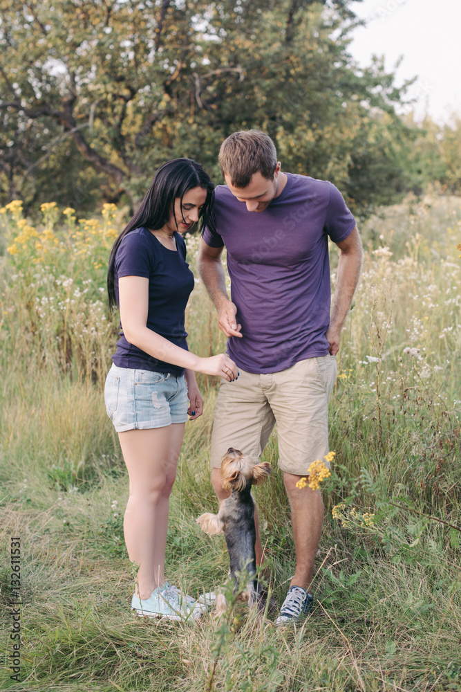 Young happy couple posing with their dog - yorkshire terrier on nature,love,lifestyle,relationship Young happy couple posing with their dog - yorkshire terrier on nature,love,lifestyle,relationship