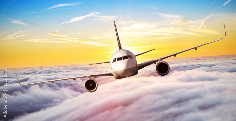 Naklejka premium Airplane flying above clouds in dramatic sunset