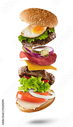 Maxi hamburger with flying ingredients on white background