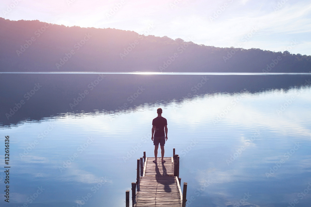Φωτογραφία dreamer, silhouette of man standing on the lake wooden pier at sunset, human str