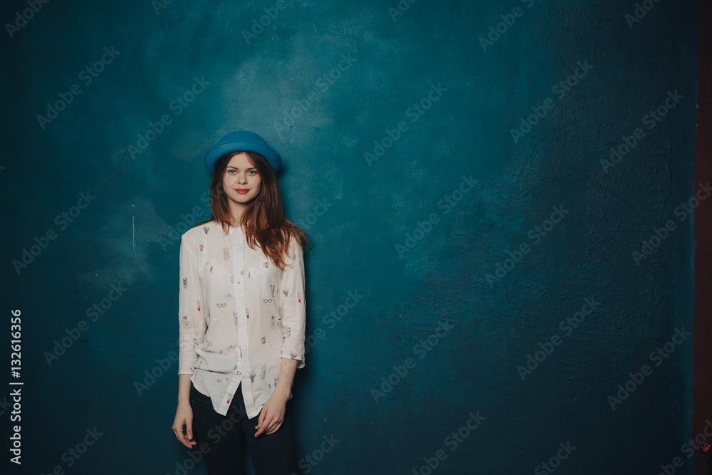 Woman in shirt holding hat, blue background Woman in shirt holding hat, blue background
