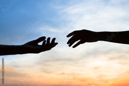 mercy, two hands silhouette on sky background, connection or help concept photo