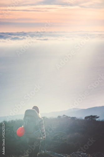 Woman Traveler with backpack hiking on cliff Travel Lifestyle concept adventure active vacations outdoor sunset aerial view from mountain summit on background