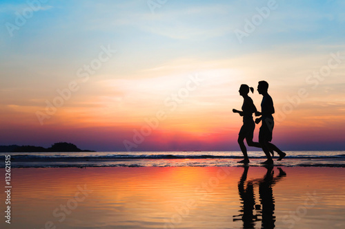 jogging and healthy lifestyle, two runners silhouettes on the beach at sunset, workout and sport