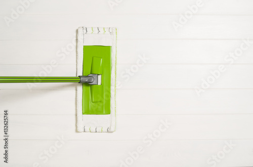 Cleaning floor with mop top view. Microfiber mop isolated on white wooden floor background. Home cleaning product concept photograph with copy space photo