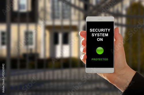 Woman holding a smartphone with home security system panel