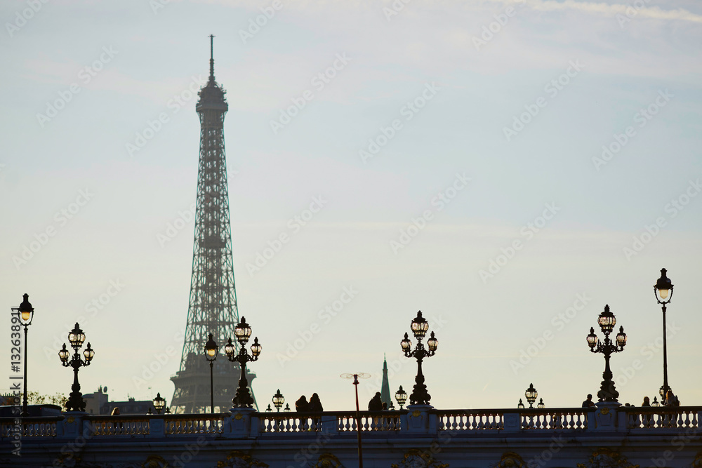Silhouettes of people and lanterns on the famous Alexandre III bridge and the Eiffel tower