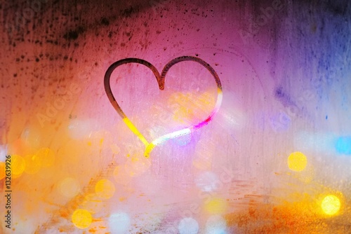 Abstract background - heart painted on a misted window on the background of colorful city lights at night