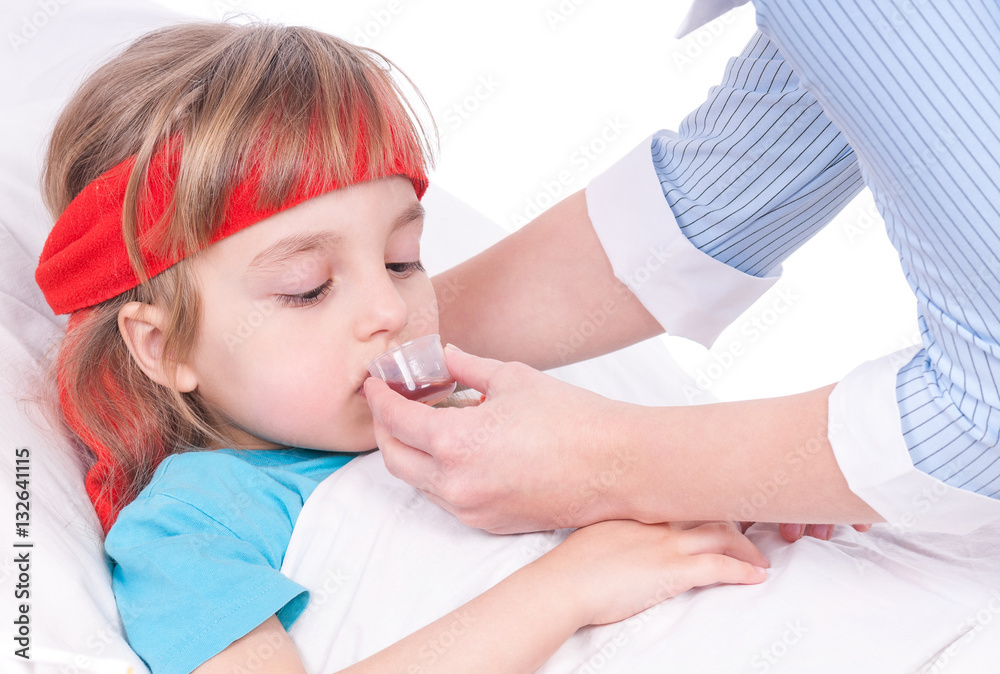 Mother giving her daughter cough syrup at home. Sick little girl in bed taking medicine with plastic cup. Mother giving her daughter cough syrup at home. Sick little girl in bed taking medicine with plastic cup.