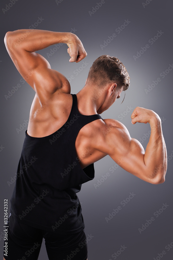 Handsome Muscular Man Posing on the Gray Background. Concept of Healthy Lifestyle.