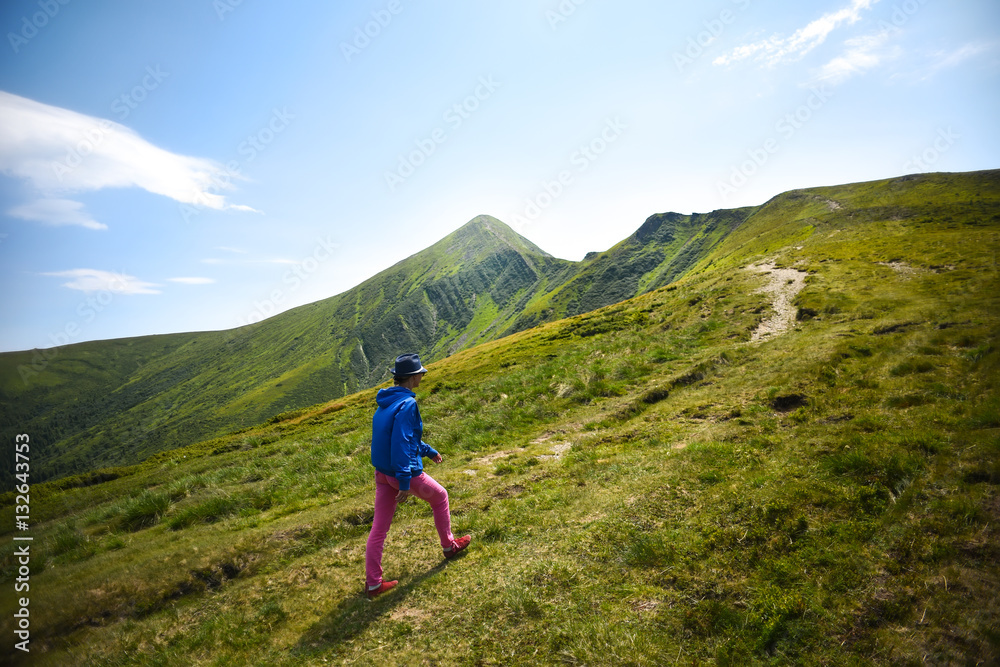 Girl going up the mountain. Young woman enjoying the beautiful scenery in the mountains