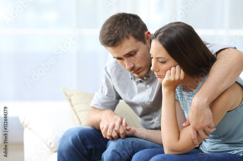 Sad couple comforting each other at home