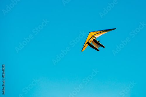 Motorized Hang Glider Flying On Blue Clear Sunny Sky Background