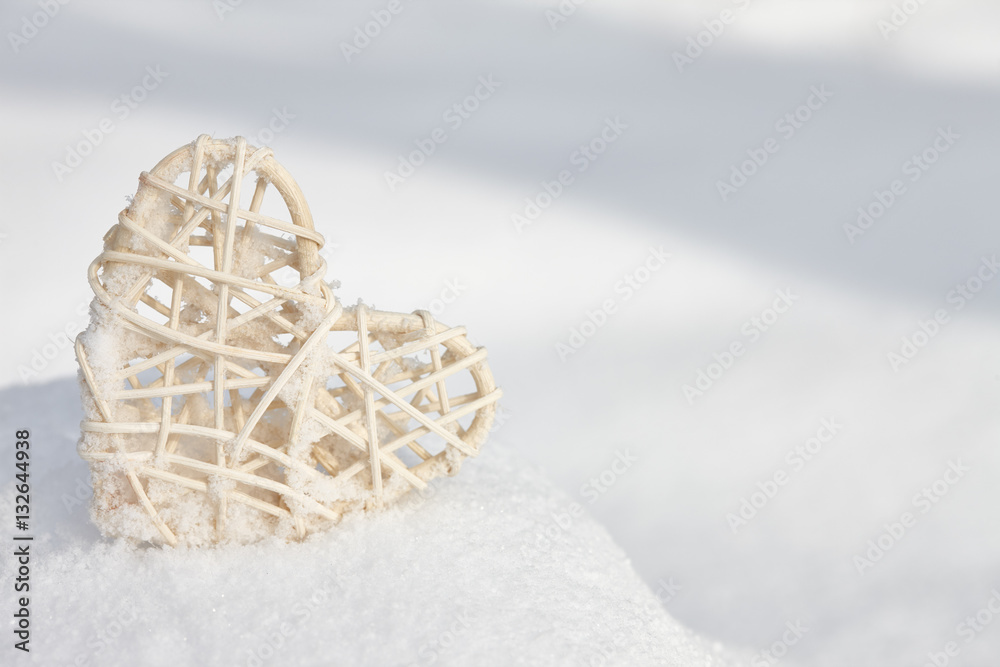Vintage rattan heart on a white snow winter background. Love and Valentines Day concept.