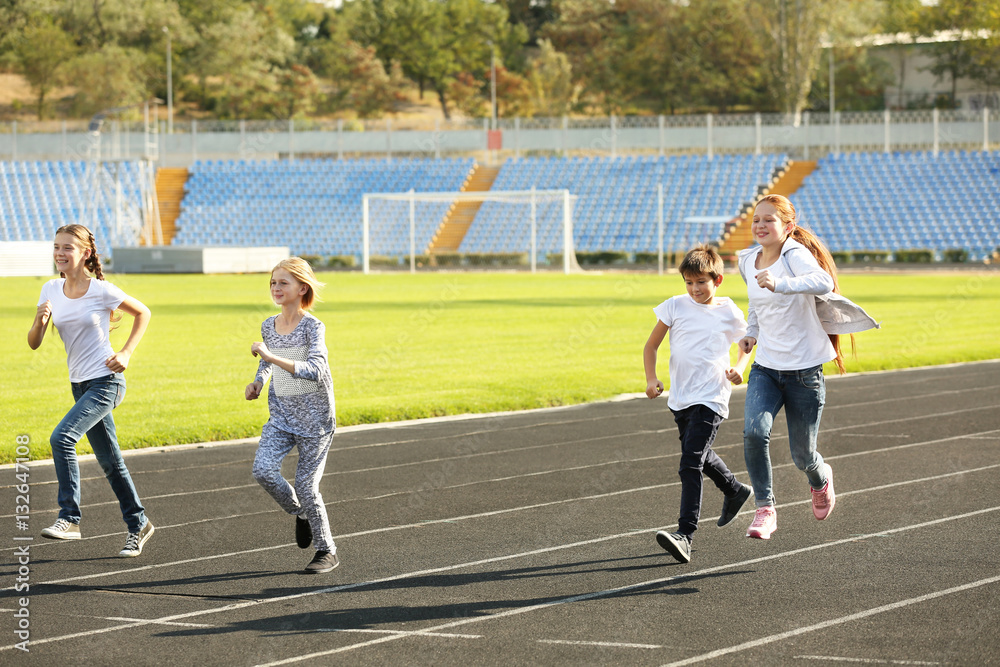Sporty children running on track at stadium