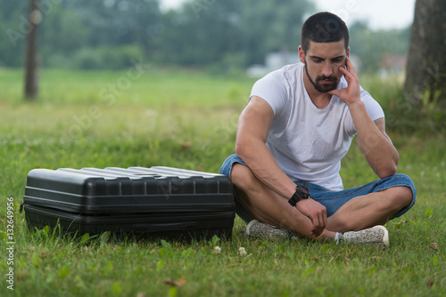 Frustrated Man Sitting On Grass With Case Drone