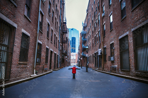 little boy standing in the middle of the street. kid in town. hands to the side. the concept of travel