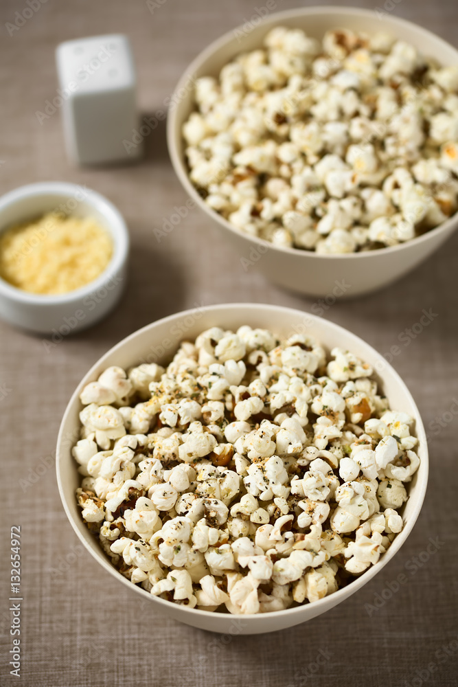 Homemade fresh savory popcorn with cheese, garlic and dried oregano in bowls, photographed with natural light (Selective Focus, Focus in the middle of the first bowl) Homemade fresh savory popcorn with cheese, garlic and dried oregano in bowls, photographed with natural light (Selective Focus, Focus in the middle of the first bowl)
