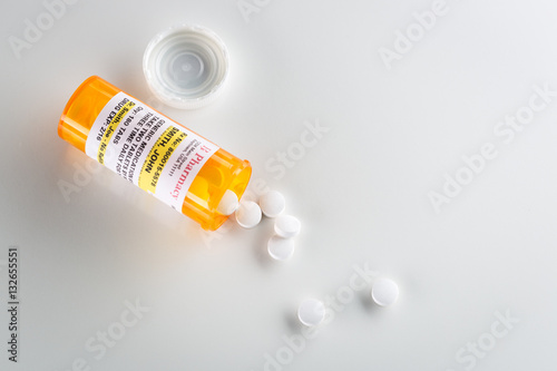 Non-Proprietary Medicine Prescription Bottle and Spilled Pills  Over Head on Grey Background.