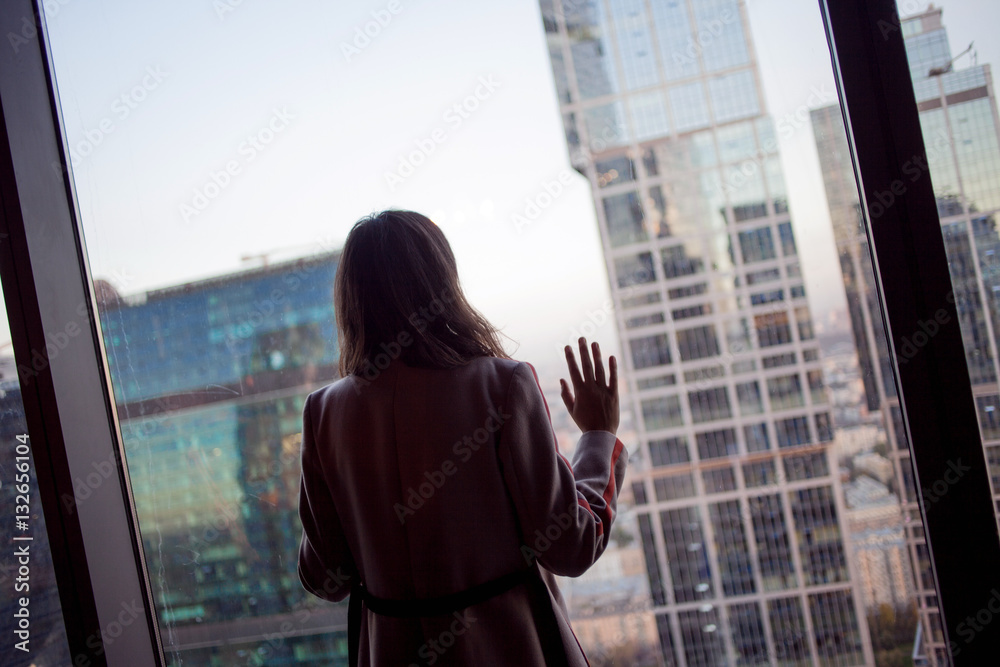Back view woman looking at the city. Watching cityscape from skyscraper interior Back view woman looking at the city. Watching cityscape from skyscraper interior
