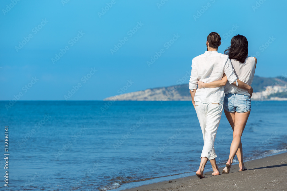 Couple walking on beach. Young happy interracial couple walking on beach smiling holding around each other. Couple walking on beach. Young happy interracial couple walking on beach smiling holding around each other.
