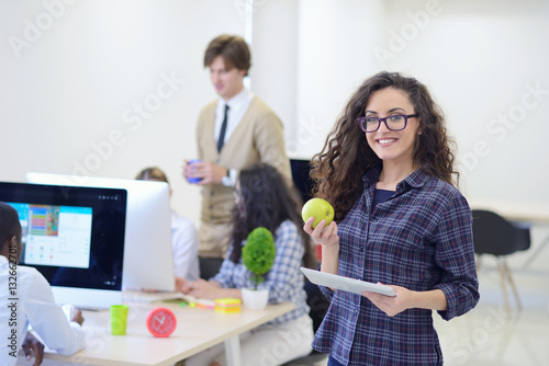 Fotografía Portrait of pretty young woman eating an apple and holding tablet in her office