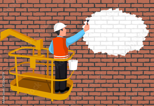 Worker standing in an assembly cradle paints a wall representing the place for your text. 