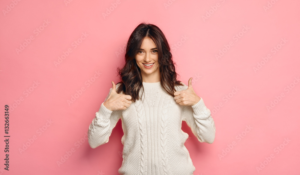 brunette woman showing thumbs up and smiling over pink background brunette woman showing thumbs up and smiling over pink background