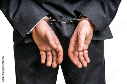 Arrested businessman in handcuffs with hands behind back