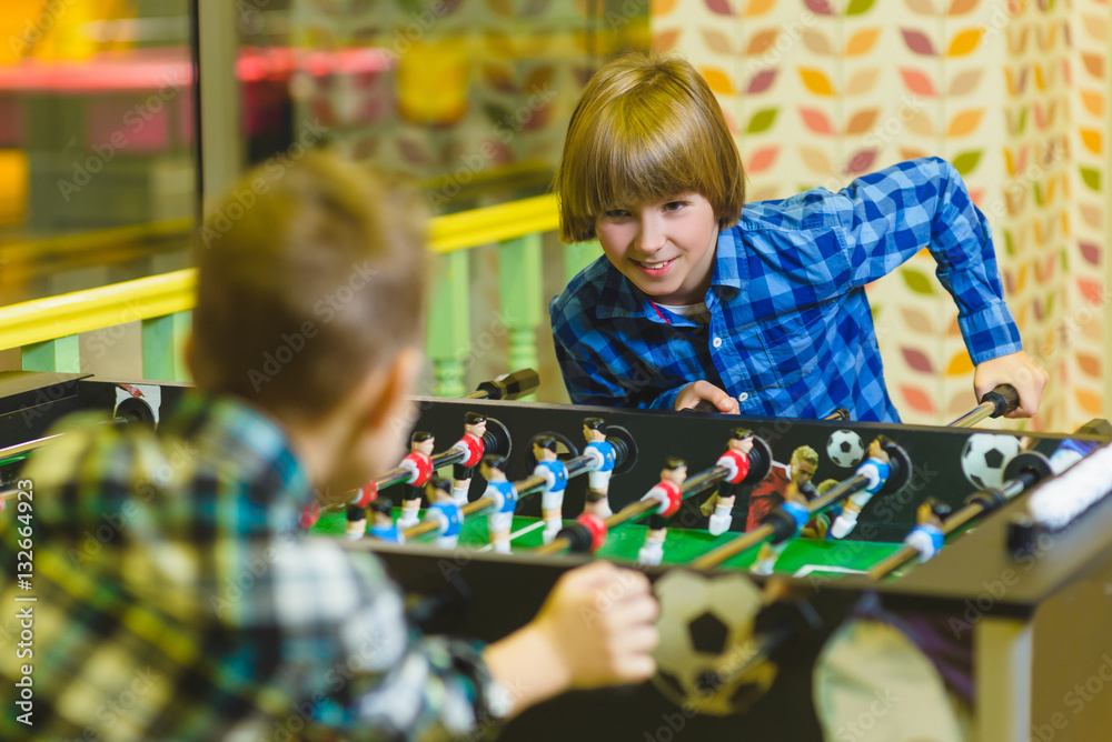 Happy boys playing table football in children room