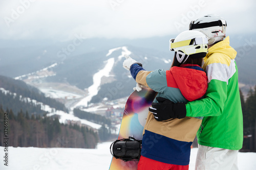 Back view picture of loving couple snowboarders