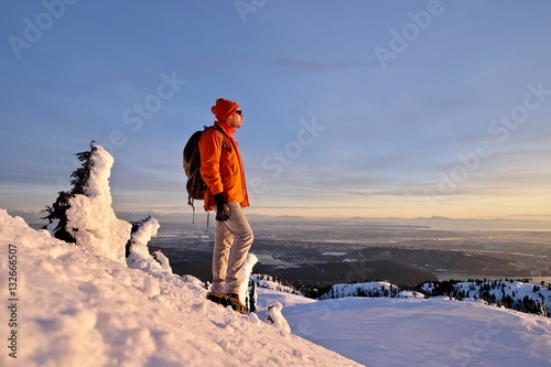 Man snowshoeing on mountain top watching sunset. Mount Seymour Provincial Park. Vancouver. British Columbia. Canada. photo