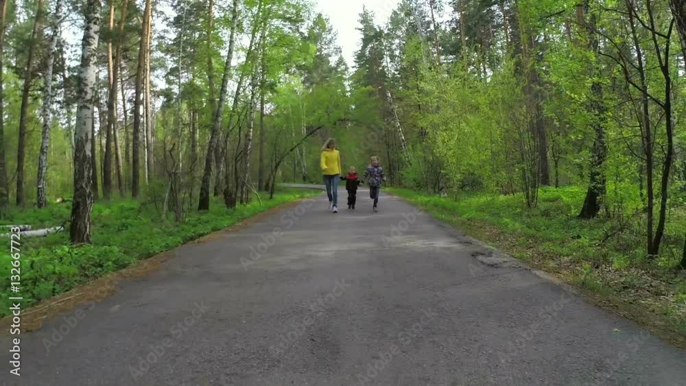 Woman and two his children hold hands and run in the forest. Slow motion
Woman and two his children hold hands and run in the forest. Slow motion