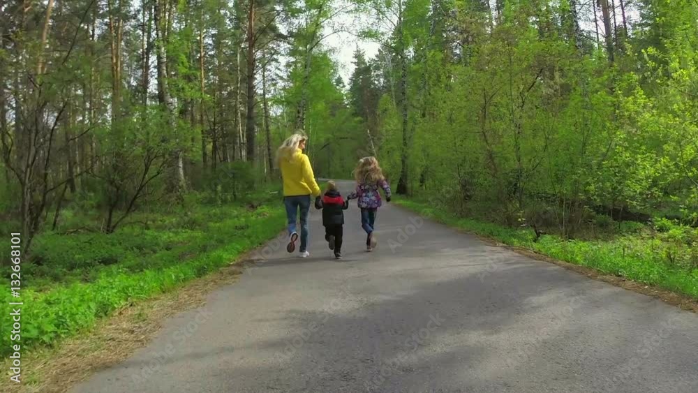 Woman and two his children hold hands and run in the forest. Slow motion
Woman and two his children hold hands and run in the forest. Slow motion