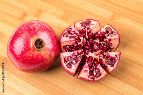 Whole and cut ripe pomegranate isolated on a wood background