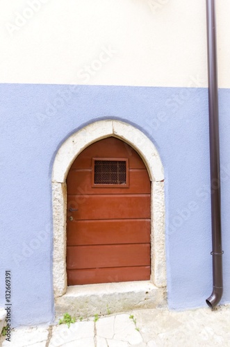 Traditional picturesque Mediterranean architecture at medieval town Vrbnik on Krk island, Croatia. View of arched wooden door, blue wall and inclined narrow alley. photo