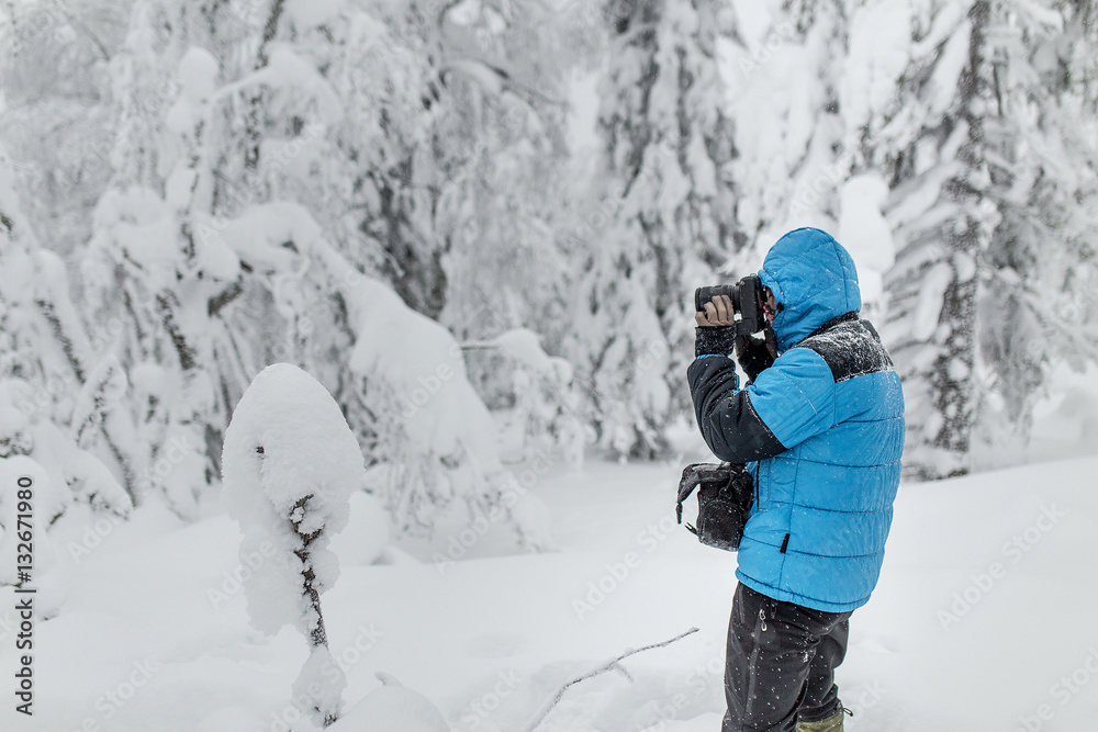 Photographer in blue jacket in winter woods