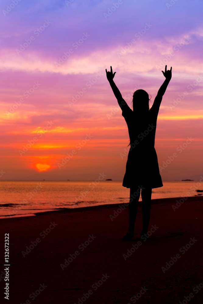 Silhouette of woman with hands up and showing I LOVE YOU sign on
