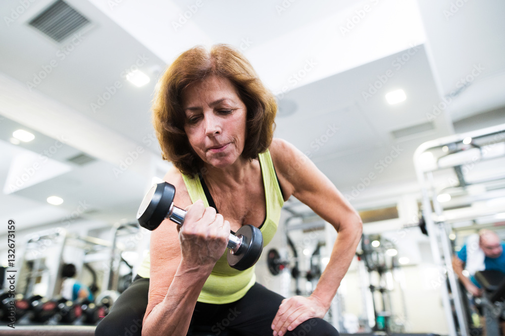 Senior woman in gym working out with weights. Senior woman in gym working out with weights.