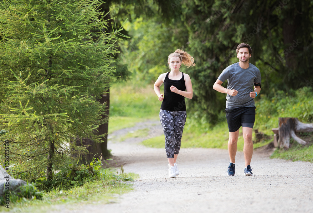 Fototapeta premium Beautiful young couple running outside in green nature.