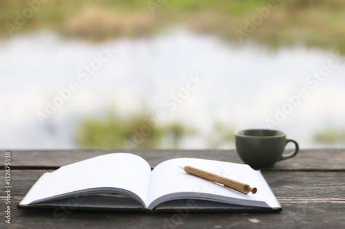 Stock Photo:.open book with pencil and office cup on a wooden ta